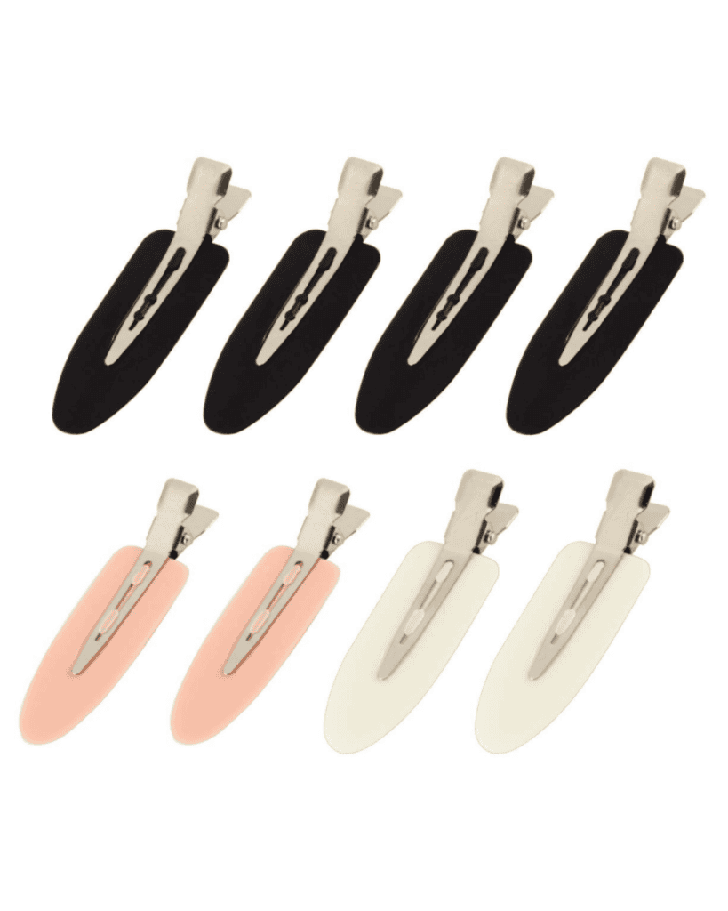 A collection of eight Beauty Essentials hair clips crafted from metal and plastic in three chic colors: three black, two pink, and three cream. Each clip features a metallic base with a sleek, elongated plastic cover for an elegant touch.