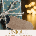 A wrapped gift with green and gold patterned paper and a twine bow sits in front of blurred warm lights. A blank brown gift tag hangs from the bow. Text reads: "Unique Cozy Gifts She'll Adore, from Cool Baking Gadgets to More - The Bargain Sisters.