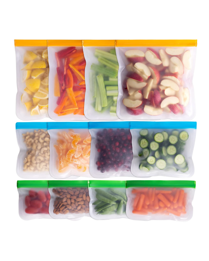 Reusable bags, acting as eco-friendly containers, are filled with various foods, including sliced lemons, carrots, celery, apples, cashews, oranges, berries, cucumber slices, cherry tomatoes, almonds, and baby carrots. They are neatly arranged in three rows on a white background.