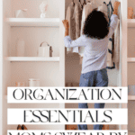 A person with curly hair wearing a light blue shirt and jeans is organizing clothes in a white closet brimming with organization essentials. The text overlay reads "Organization Essentials Moms Swear By - The Bargain Sisters." Shelves filled with planners, decor, and storage boxes complete the tidy scene.