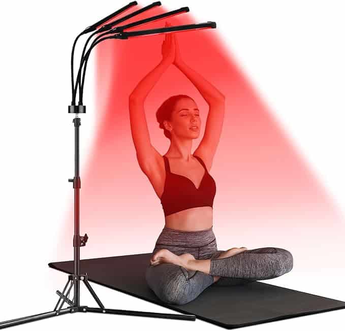 A woman sits cross-legged on a black mat, meditating with her hands in prayer pose above her head, illuminated by the red glow of a four-headed lamp beside her. Clad in a black sports bra and gray leggings, she embodies serenity amidst the day's chaos of Wednesday Deals.