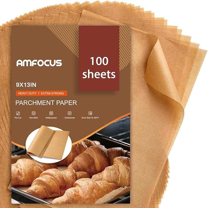 Discover Tuesday Deals on a package of 100 sheets of Amfocus parchment paper, perfectly sized at 9x13 inches. The packaging highlights features like heavy duty, extra strong, non-stick, and multipurpose use. Enjoy freshly baked croissants displayed on the paper for inspiration.