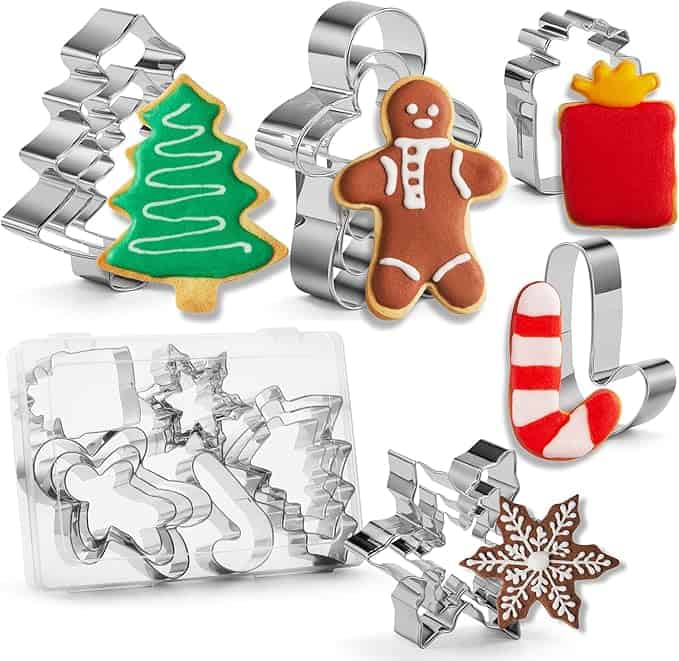 Assorted metal cookie cutters and decorated cookies feature a Christmas tree, gingerbread person, gift box, candy cane, snowflake, and come with a clear plastic storage box. Perfect for baking enthusiasts looking to snag these festive delights during our Monday Deals!