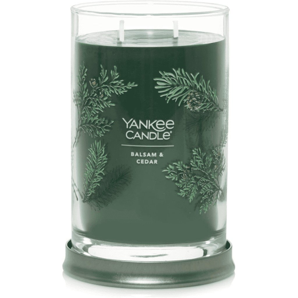 A tall, green Yankee Candle with two wicks, labeled "Balsam & Cedar," is part of our exclusive Thursday Deals. The glass jar is beautifully decorated with images of pine branches and cones, sitting elegantly on a silver metal base.