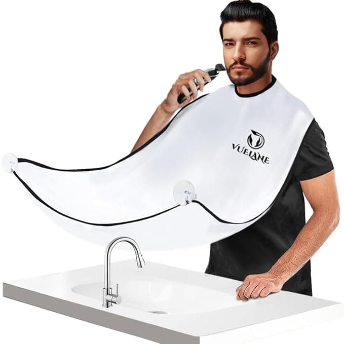 A man, taking advantage of irresistible Wednesday Deals, uses a beard trimming cape attached to the bathroom mirror with suction cups. The white cape efficiently catches trimmed hairs over the sink as he skillfully operates his trimmer, all while sporting a sleek black shirt.