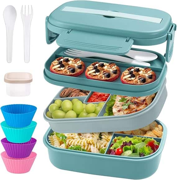 A teal bento lunch box with Thursday Deals boasts two stackable compartments. The top layer holds mini pizzas and utensils, while the bottom has grapes, pasta salad, grilled chicken, and veggies. It includes a small sauce container and colorful silicone muffin cups.