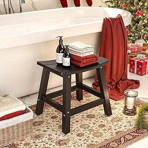 A wooden bath stool with toiletries, towels, and red fabric is perched beside a white bathtub. Nearby, a Christmas tree adorned with ornaments and presents rests on a patterned rug. Don't miss out on Thursday Deals to add festive charm without breaking the bank.