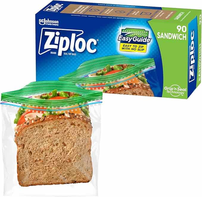 A box of Ziploc brand sandwich bags is shown, featuring "EasyGuide" and "Grip 'n Seal Technology" labels, perfect for your Thursday Deals. In front, a sandwich is visible in a clear Ziploc bag. The box indicates it contains 90 bags.