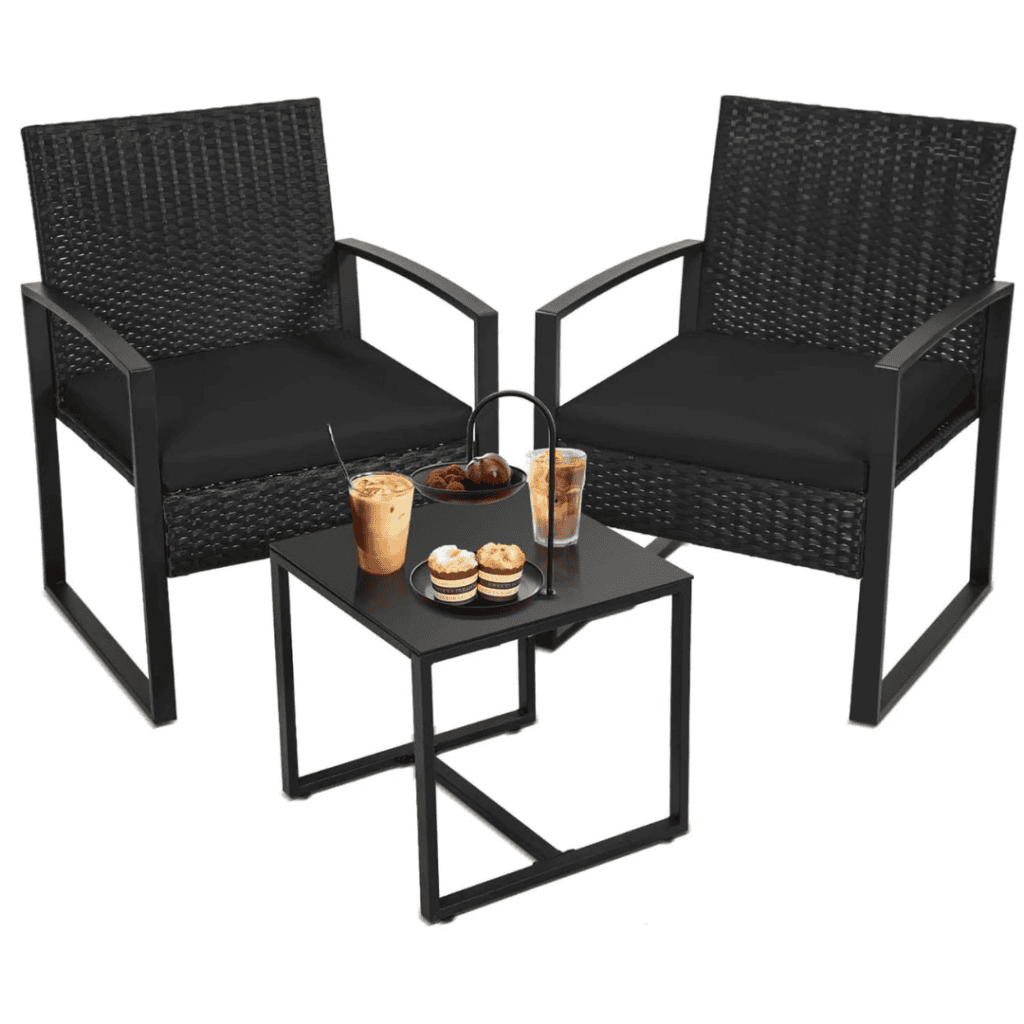 Two black wicker chairs with cushions flank a small square table. On the table are two iced coffees, a plate of macarons, and a bowl of cherries. This cozy spot for two is perfect for enjoying Friday deals in style.