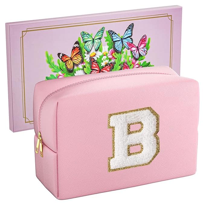 A pink cosmetic bag with a large white letter "B" outlined in gold on the front is part of our exclusive Thursday Deals. Behind it, a floral card featuring colorful butterflies adds a touch of whimsy.