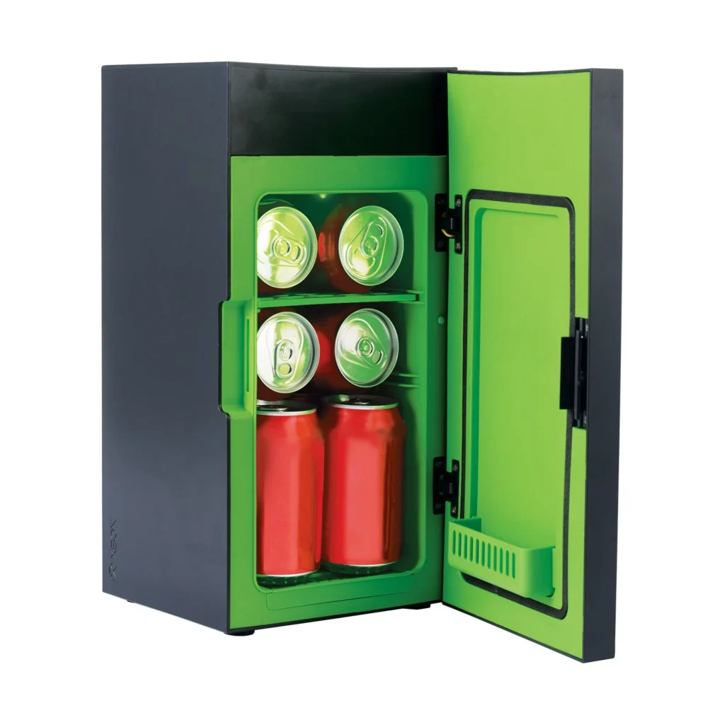 A compact black fridge with a vibrant green interior showcases four soda cans on the top shelf and two taller red cans below. The open door reveals its sleek design, perfect for Tuesday Deals.