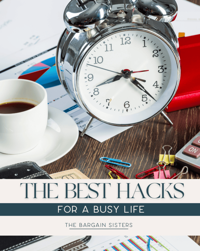 An alarm clock, coffee cup, graphs, and office supplies on a desk. The text reads, "The Best Hacks for a Busy Life – The Bargain Sisters.