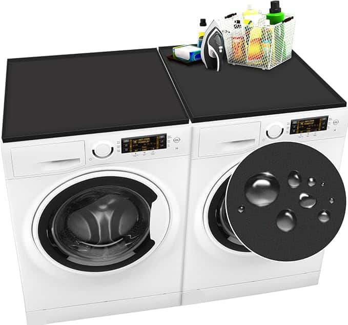 Two white front-loading laundry machines sit side by side, their tops adorned with black, waterproof mats. An iron and a basket with cleaning supplies rest on one mat, highlighting the convenience of Monday Deals. A magnified inset showcases water droplets on the mat's surface.