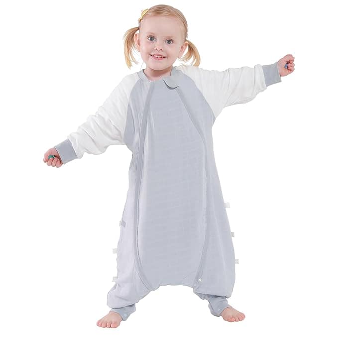 A child with blonde hair in pigtails is smiling and standing with arms outstretched, wearing a gray and white oversized onesie, ready for fun. It's a bright moment that could make any Wednesday Deals extra special against the plain white background.