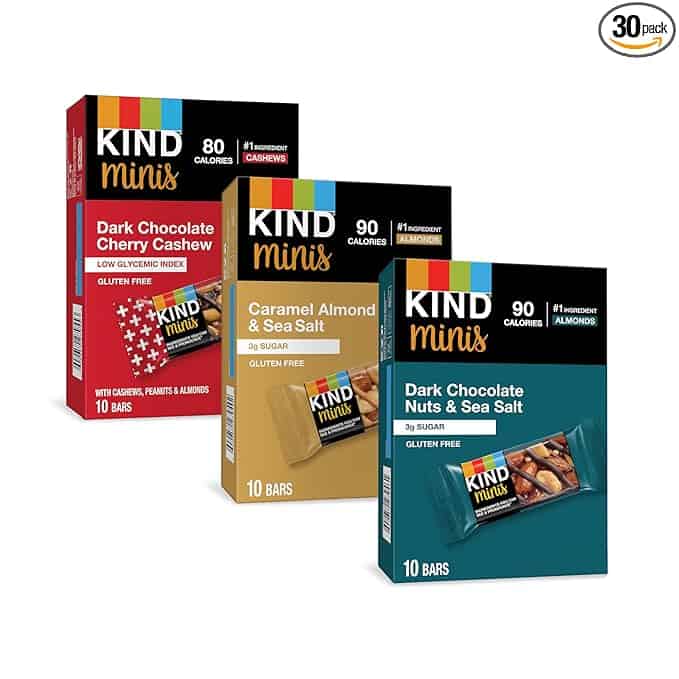 Three boxes of KIND Minis snack bars are part of our exciting Friday Deals: Dark Chocolate Cherry Cashew (red), Caramel Almond & Sea Salt (beige), and Dark Chocolate Nuts & Sea Salt (brown). Each box has 10 bars with key ingredients showcased on the front.