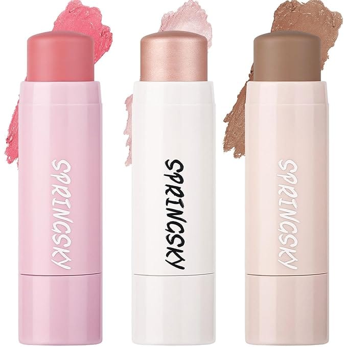 Three SPRINGSKY stick makeup products are artfully displayed: the left in pink, the middle in shimmery champagne, and the right in warm brown. Smudges of each color are shown behind the sticks, all available now with Thursday Deals for a perfect beauty bargain.