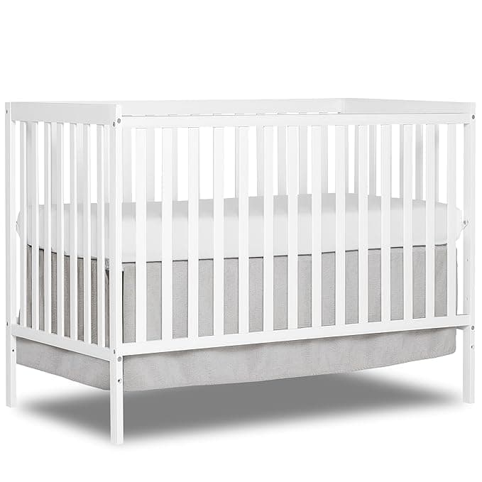 White baby crib with slatted sides and a simple, modern design, perfect for Friday Deals. It features a light gray mattress and skirt, set against a white background.