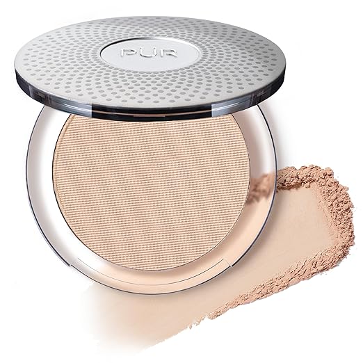 A compact of PUR pressed powder with the lid open, showcasing the product inside. Beside it, a sample of the loose powder is spread on a white surface. The compact features a textured silver top with the brand logo—perfect for those Friday Deals you can't resist!.