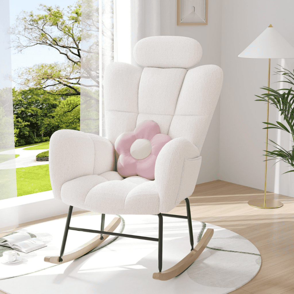 A modern white rocking chair with a pink flower-shaped pillow rests on a circular rug in a bright room. Sunlight streams through the window, illuminating a green lawn outside. A tall floor lamp stands nearby, casting subtle light during Tuesday Deals afternoons.