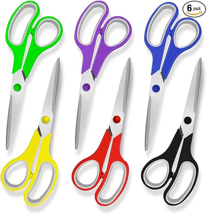 Six pairs of scissors with colorful handles—green, purple, blue, yellow, red, and black—are neatly arranged in two rows. Each pair boasts metallic blades and a circular pivot screw. "6 pack" is noted in the top right corner. Don't miss out on these Wednesday Deals!.