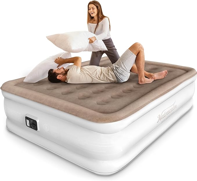 A woman playfully holds a pillow above a man lounging on a large, beige inflatable mattress. The man shields himself with another pillow, both smiling in this lighthearted moment, perhaps enjoying their new finds from the Wednesday Deals.