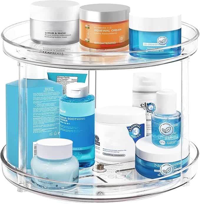 A two-tier clear rotating organizer, available in this week's Tuesday Deals, holds diverse skincare products, including creams and gels in jars and bottles, with packaging predominantly in shades of blue, white, and orange.