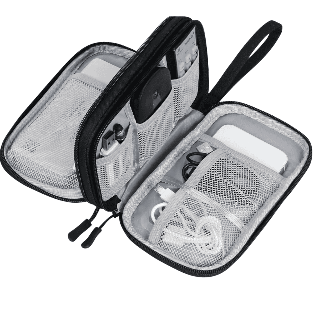 A black zippered electronics organizer is open, showcasing several compartments with packing tips in mind, holding various cables, a power bank, a remote control, and other small tech accessories. The mesh compartments offer clear visibility.